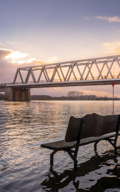 Bench in water with bridge in the background in Deventer, The Netherlands